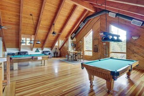 Ein Holzinnenraum mit Billardtisch, Deckenventilatoren und einem Essbereich.
