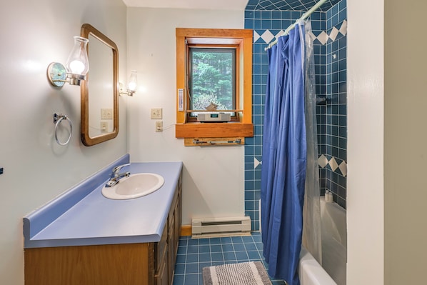 A bathroom with a sink, mirror, window, shower curtain, and tiled floor. - Kenway Ranch: Family Retreat Near Acadia Trails (Southwest Harbor)