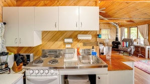 A kitchen with white cabinets, a stove, and a sink. - Waterfront Berkshires Studio w/ Dock on Goose Pond (Lee)