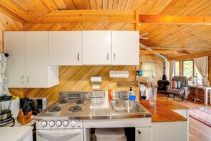 A kitchen with white cabinets, a stove, and a sink. - Waterfront Berkshires Studio w/ Dock on Goose Pond (Lee)