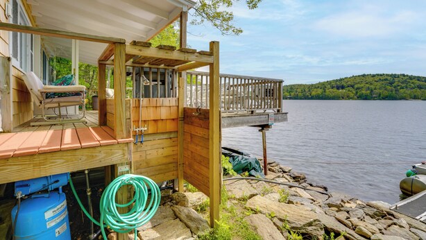 A wooden dock extending over a lake, a boat, and a cabin with a deck. - Waterfront Berkshires Studio w/ Dock on Goose Pond (Lee)