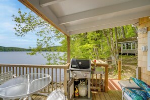A covered deck with a grill, a table, and a chair. - Waterfront Berkshires Studio w/ Dock on Goose Pond (Lee)