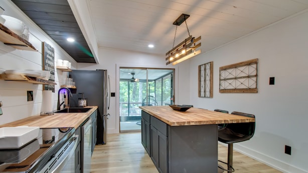 Una cucina moderna con piani in legno, un'isola centrale, sgabelli da bar e vista sull'esterno.