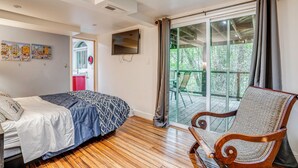 A bedroom with a bed, a chair, a TV, and a sliding glass door leading to an outdoor area. - Hike, Golf & Explore: Extended Stay in Camp Meeker (Occidental)