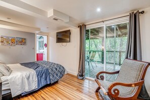 A bedroom with a bed, a chair, a TV, and a sliding glass door leading to an outdoor area. - Hike, Golf & Explore: Extended Stay in Camp Meeker (Occidental)