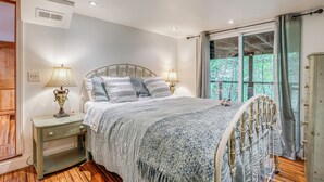 A bedroom with a bed, nightstands, lamps, a window with curtains, and a view of trees. - Hike, Golf & Explore: Extended Stay in Camp Meeker (Occidental)