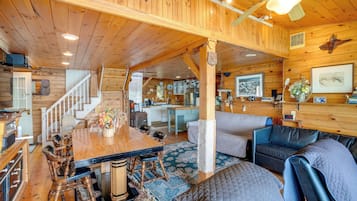 Ein Holzblockhaus-Interieur mit Essbereich, Sofa, Küche und Treppe.