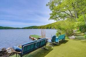 A lakeside setting with a dock, boats, and outdoor seating.