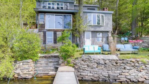 A two-story cabin with a stone staircase leading to a wooden deck, surrounded by trees. - Lakeside Berkshires Cabin w/ Private Dock & Views (Lee)