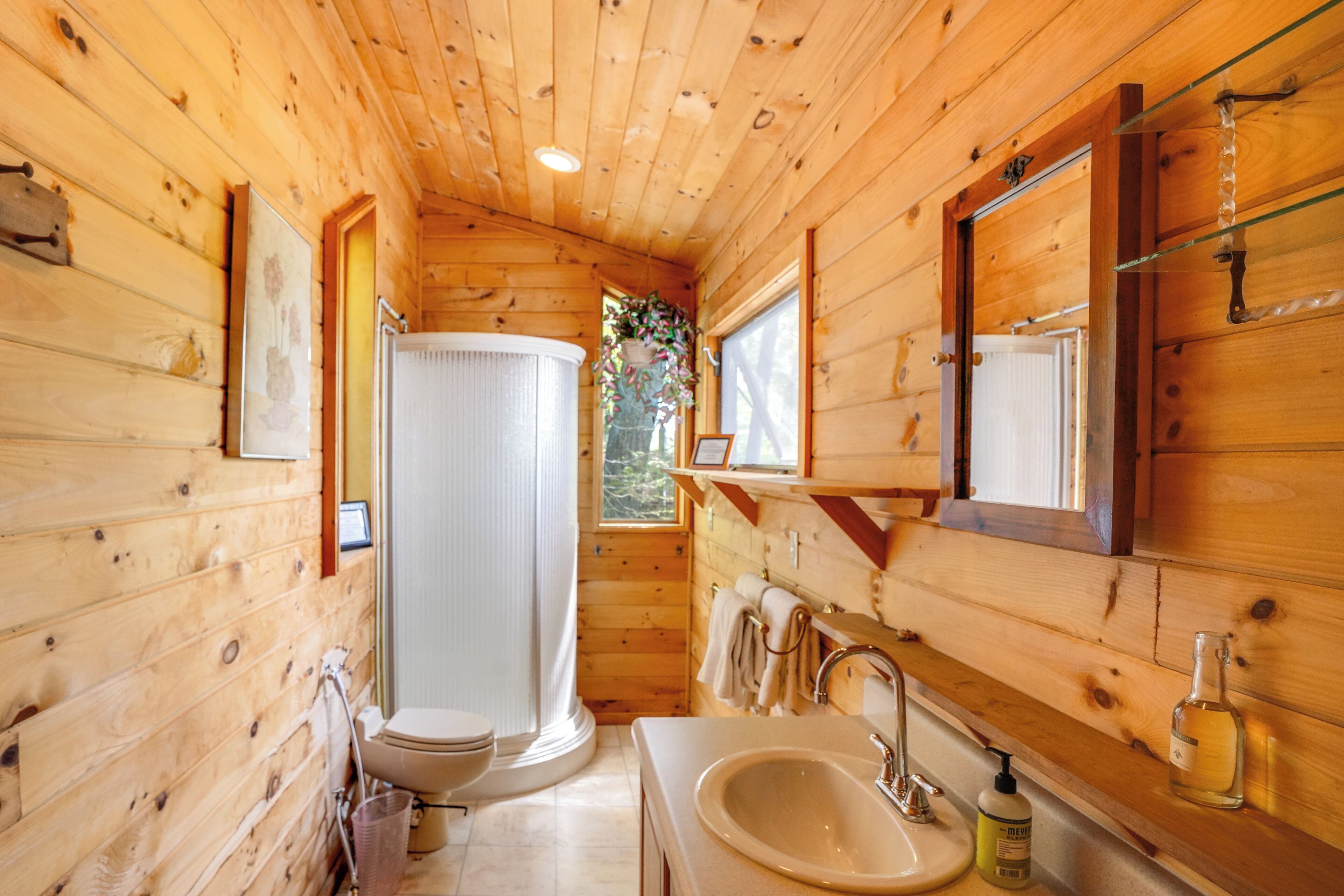 Ein Badezimmer einer Holzhütte mit Toilette, Waschbecken und Dusche.