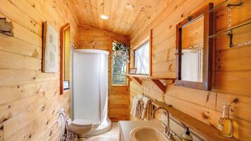 Ein Badezimmer einer Holzhütte mit Toilette, Waschbecken und Dusche.