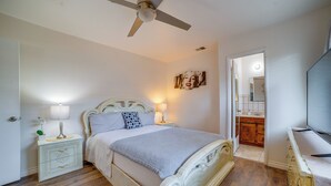 A bedroom with a bed, nightstands, a ceiling fan, a wall-mounted TV, and a door leading to a bathroom. - Commuter Friendly! Extended Stay in Riverside (Riverside)