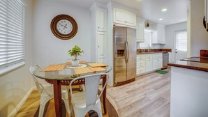 A kitchen with white cabinets, a stainless steel refrigerator, and a dining table with chairs. - Commuter Friendly! Extended Stay in Riverside (Riverside)