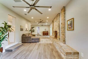 A spacious living room with a stone fireplace, a ceiling fan, and a large sectional sofa. - Patio w/ Views! Pet-friendly Keystone Heights Home (Keystone Heights)