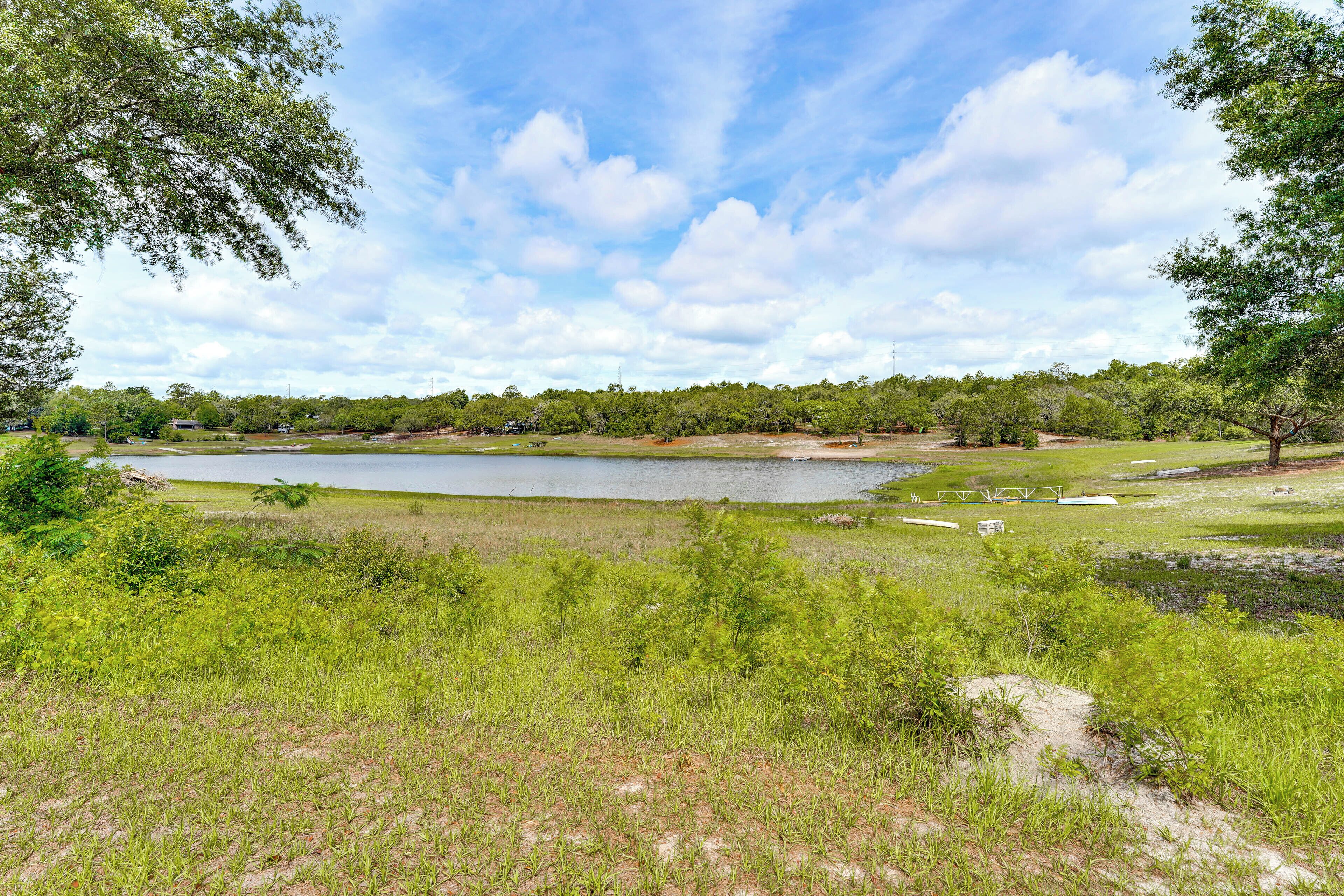 A natural landscape with a lake, trees, and grassy areas.