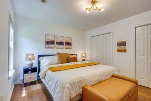 Quarto com cama, mesas de cabeceira, um banco, luminária na parede e lumin ária no teto.