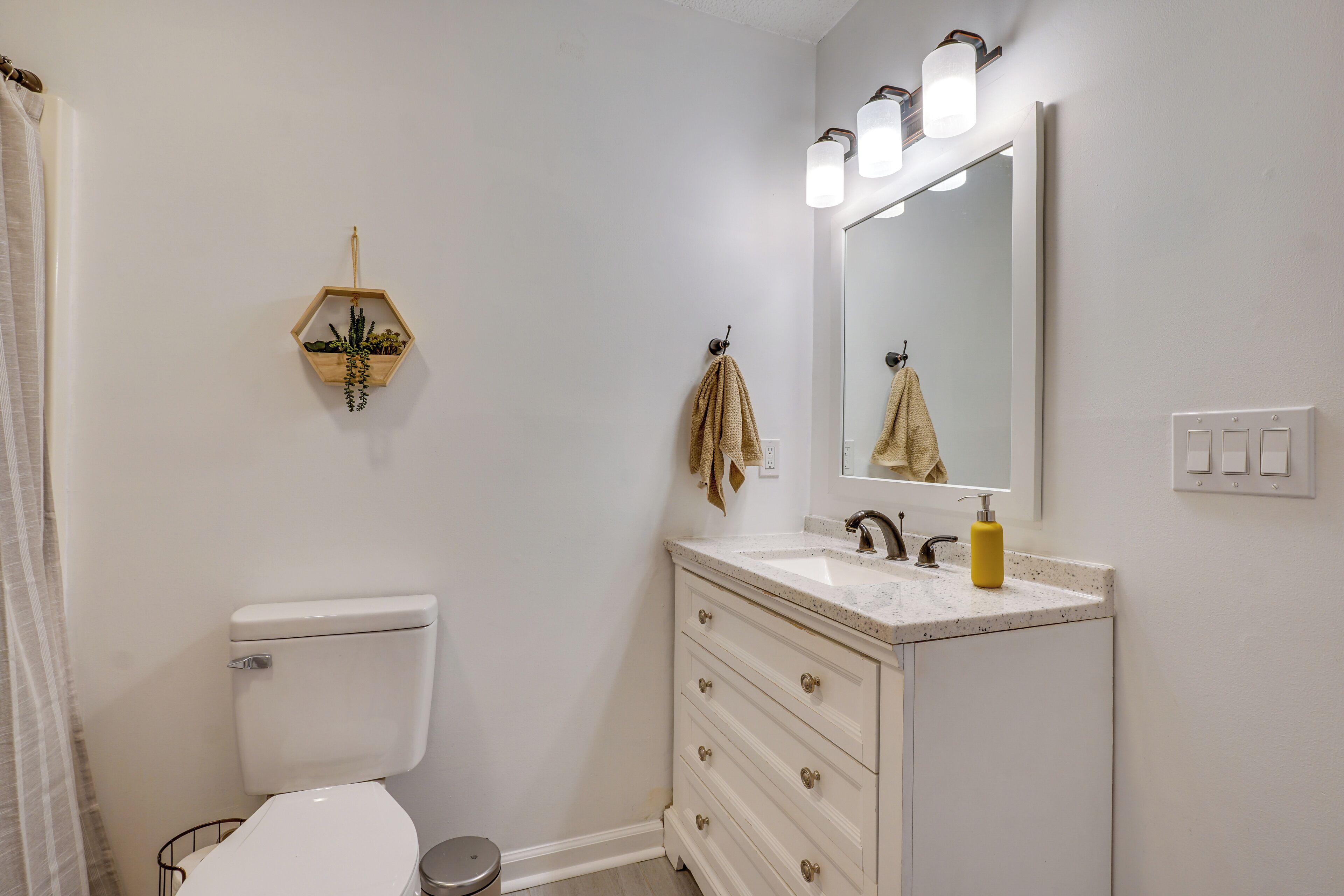 Ein Badezimmer mit Toilette, Waschbecken mit Spiegel und Handtuchhalter.