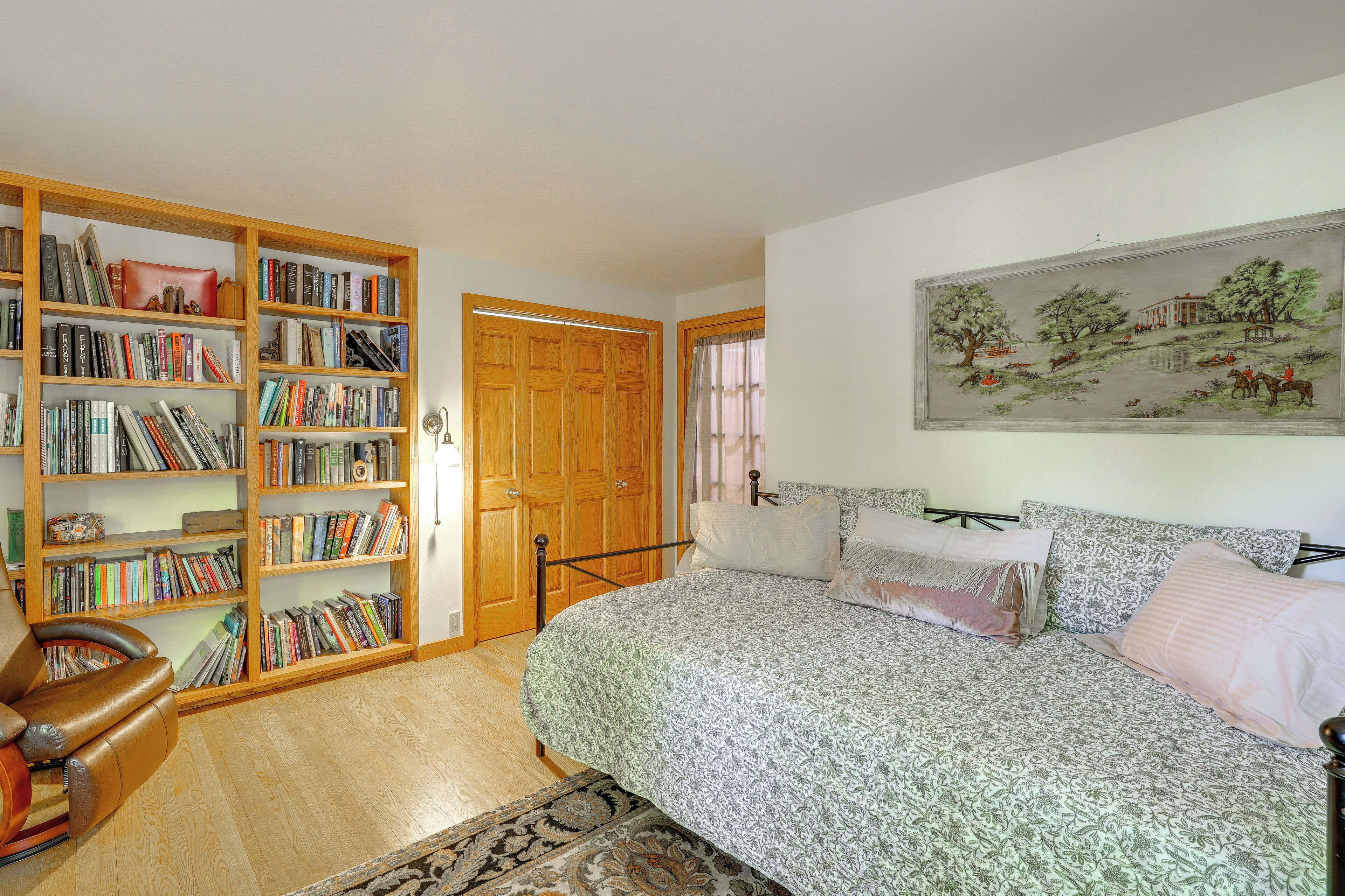 Un dormitorio con una cama grande, una estantería, una puerta de madera y un cuadro en la pared.