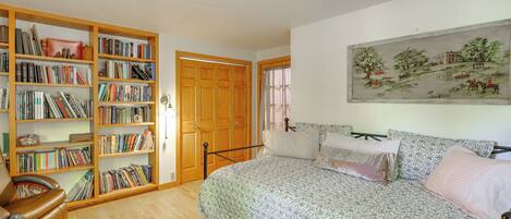Un dormitorio con una cama grande, una estantería, una puerta de madera y un cuadro en la pared.