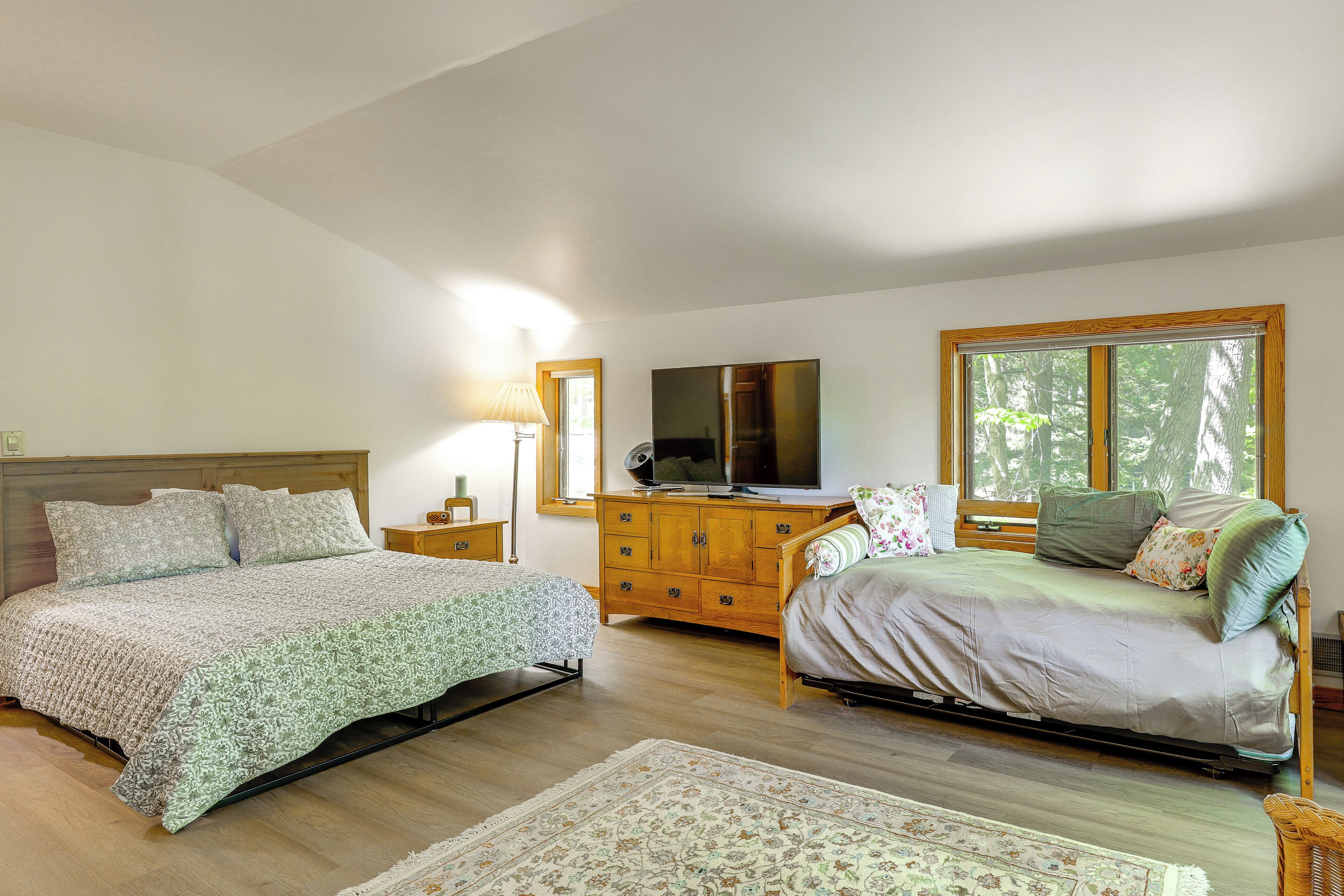 Een slaapkamer met een bed, een dressoir, een televisie en een raam.