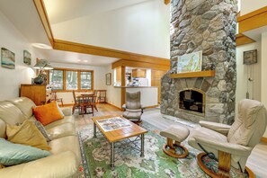 A spacious living area with a stone fireplace, leather furniture, and a view of the kitchen.