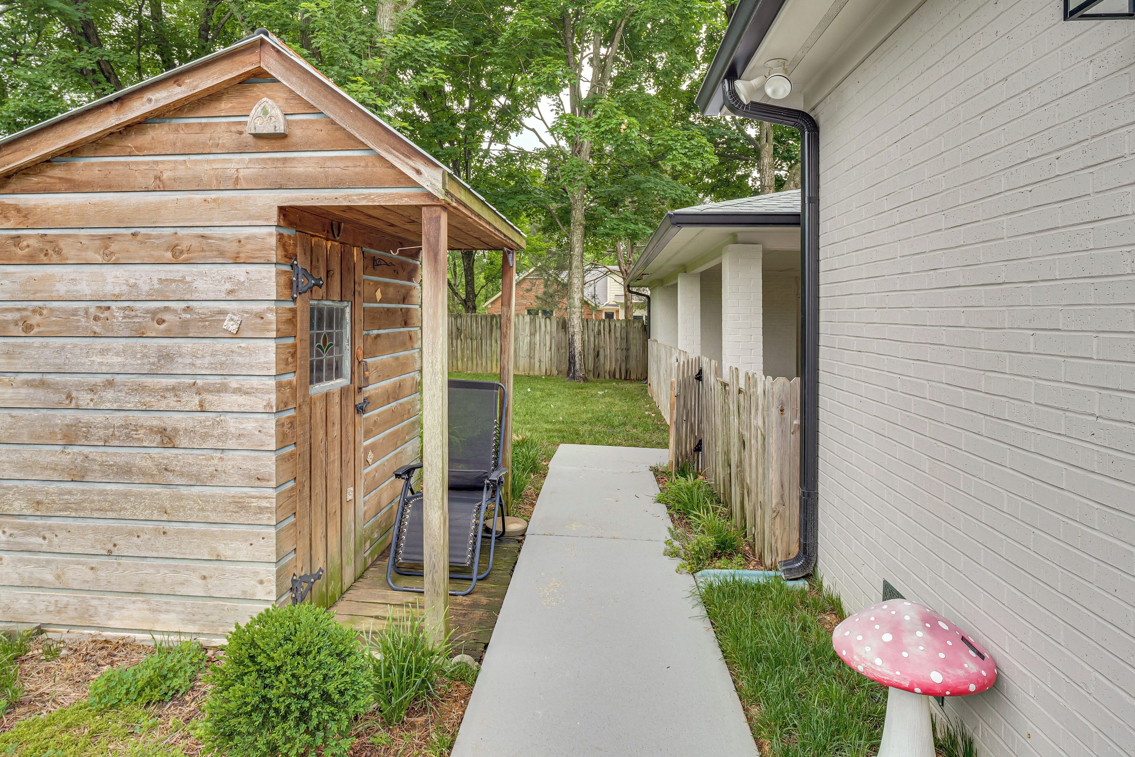 A wooden cabin with a porch and a pathway leading to a house.