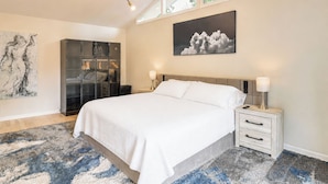 Ein Schlafzimmer mit Bett, Nachttischen, einem Kleiderschrank, einem großen abstrakten Gemälde und einem Wandbild mit einer Wolke.