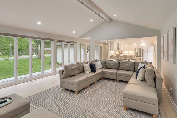 A modern living room with a sectional sofa, a dining area, and large windows. - Game Room! Upscale Family Retreat in Murfreesboro (Murfreesboro)