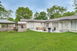 Ein zweistöckiges Haus mit überdachter Terrasse, Grillplatz und kleinem, eingezäunten Garten.