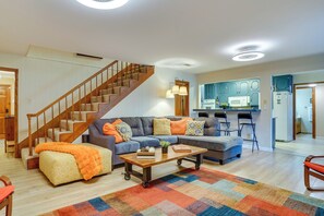A living room with a sofa, coffee table, and a staircase. - Hot Tub & Game Room! Home 15 Mi to At&t Stadium (North Richland Hills)