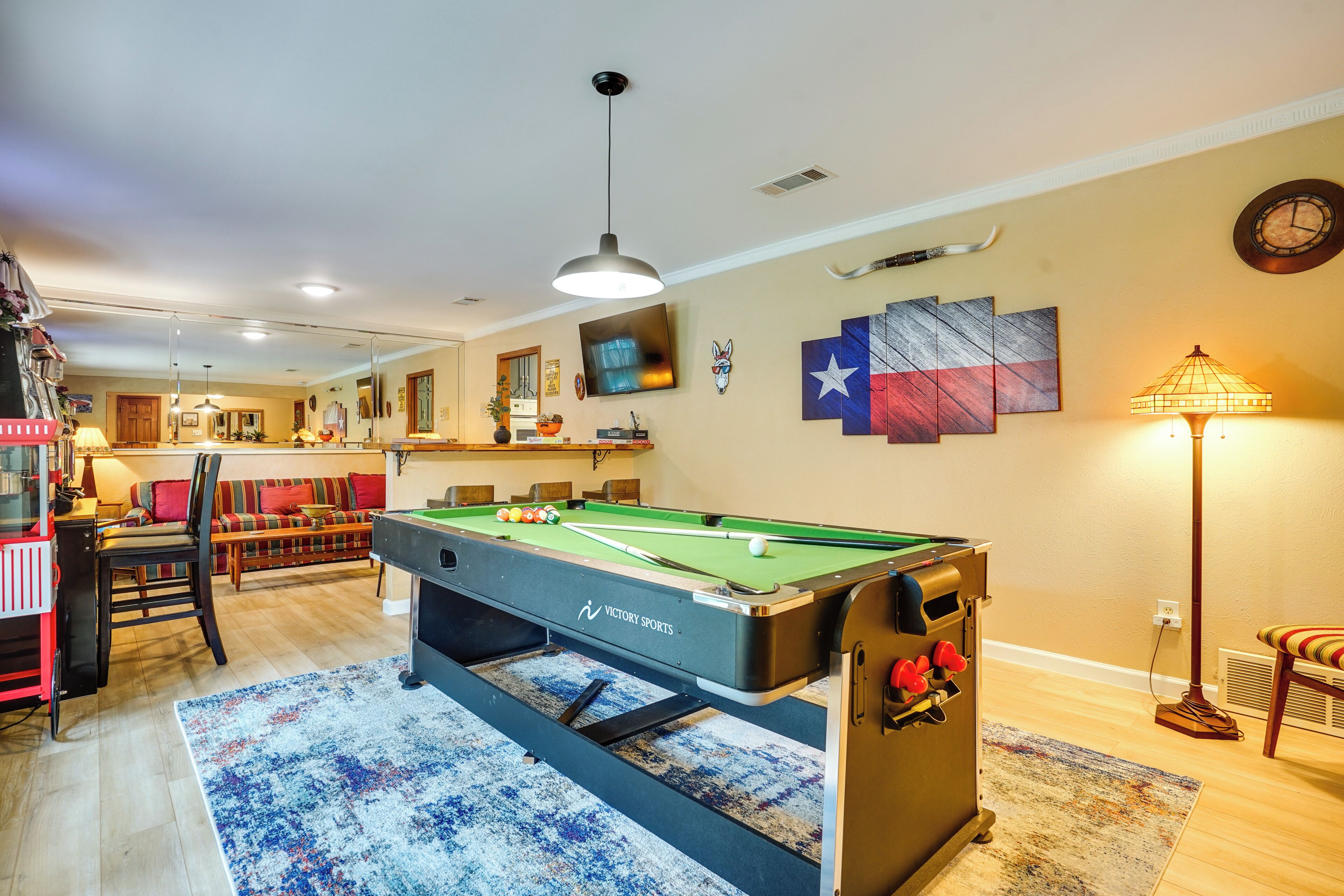 A pool table with a cue ball, a sofa, and a dining area with chairs and a table.
