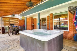 Ein Whirlpool in einem Außenbereich mit Terrasse, einer Ziegelwand, einer Holzbeschichtung und einem Tisch mit Stühlen.