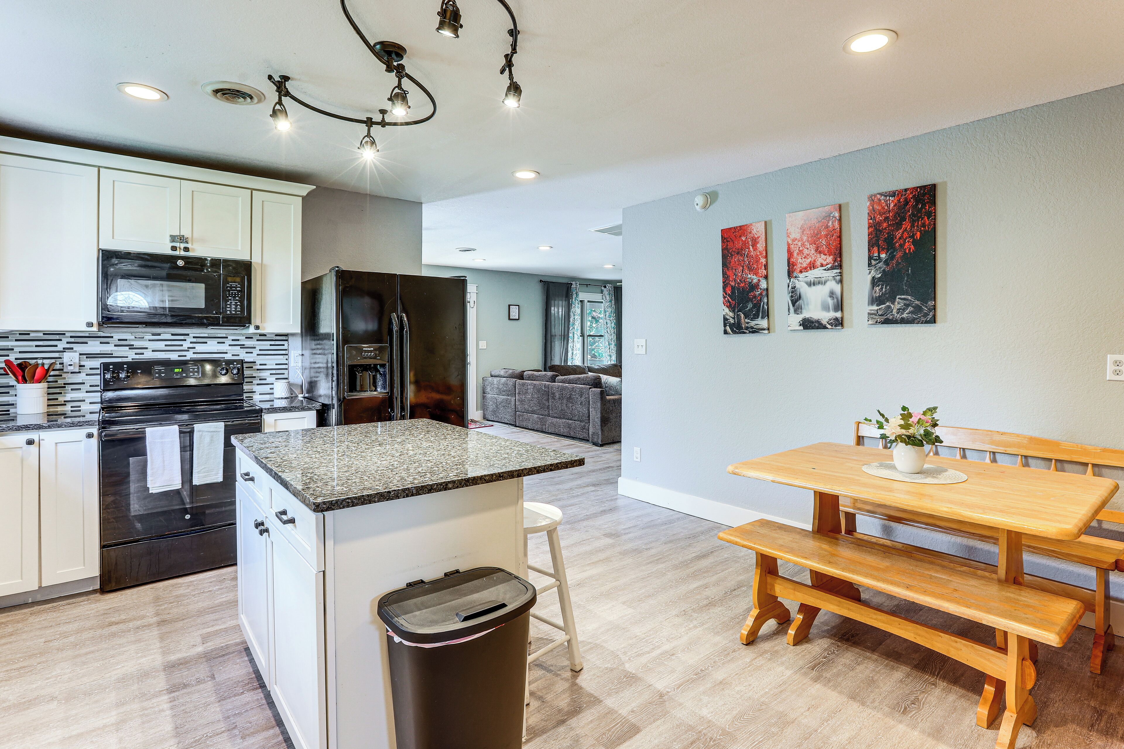 A modern kitchen with granite countertops, stainless steel appliances, and a wooden dining table with benches.