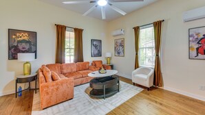A living room with a sectional sofa, a round coffee table, a white armchair, and a ceiling fan.