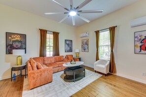 Una sala de estar con un sofá modular, una mesa redonda de centro, un sillón blanco y un ventilador de techo.