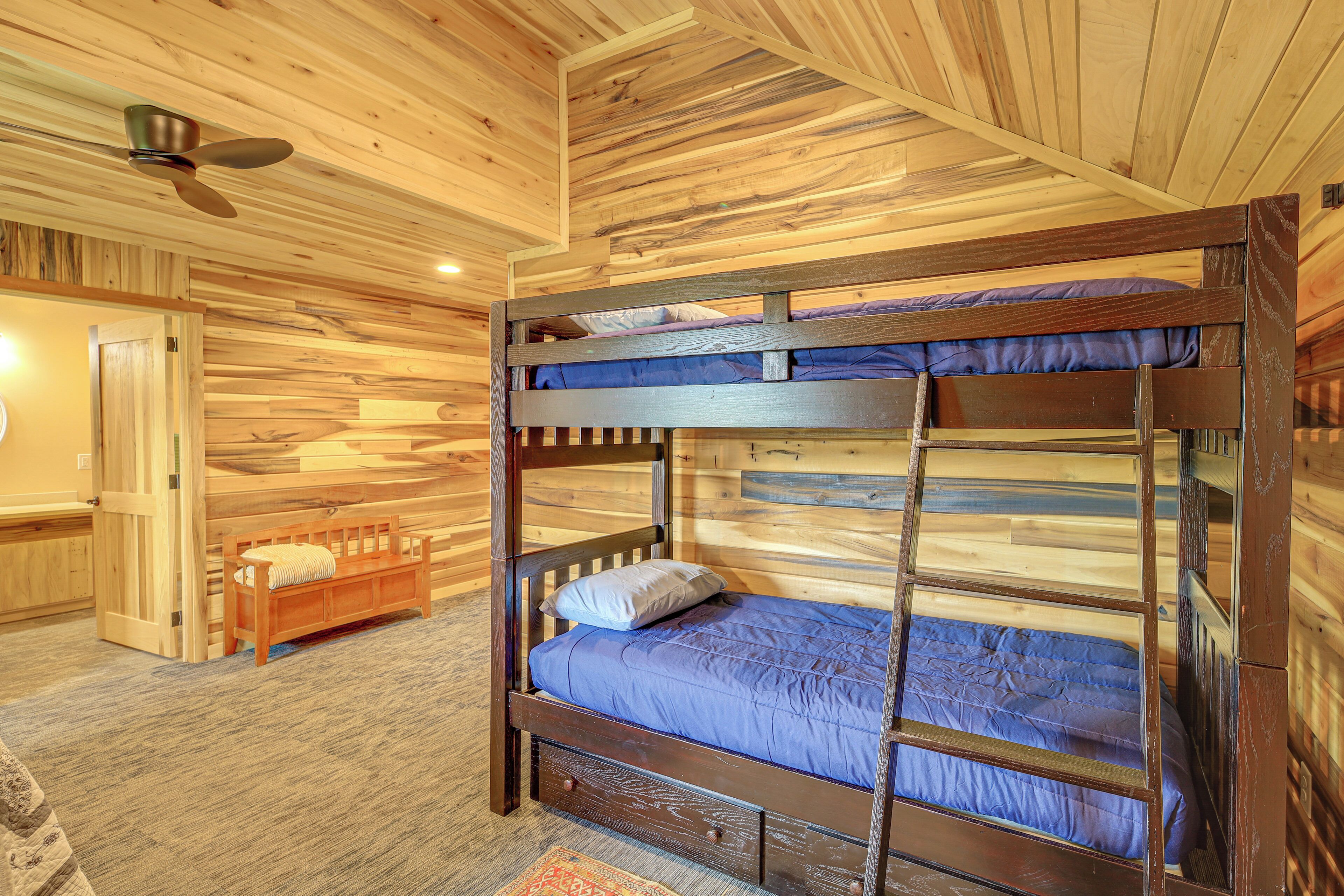 A bunk bed with a wooden frame and blue bedding, a wooden bench, and a door with a wooden panel.
