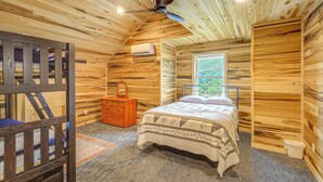 A wooden cabin bedroom with a bed, dresser, and window. - Pet-friendly Home w/ Stunning Views in Sparta! (Sparta)