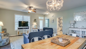 A living room with a television, ceiling fan, chandelier, dining table, and a kitchen area in the background. - Shared Pool & Hot Tub! Seaside Murrells Inlet Home (Murrells Inlet)