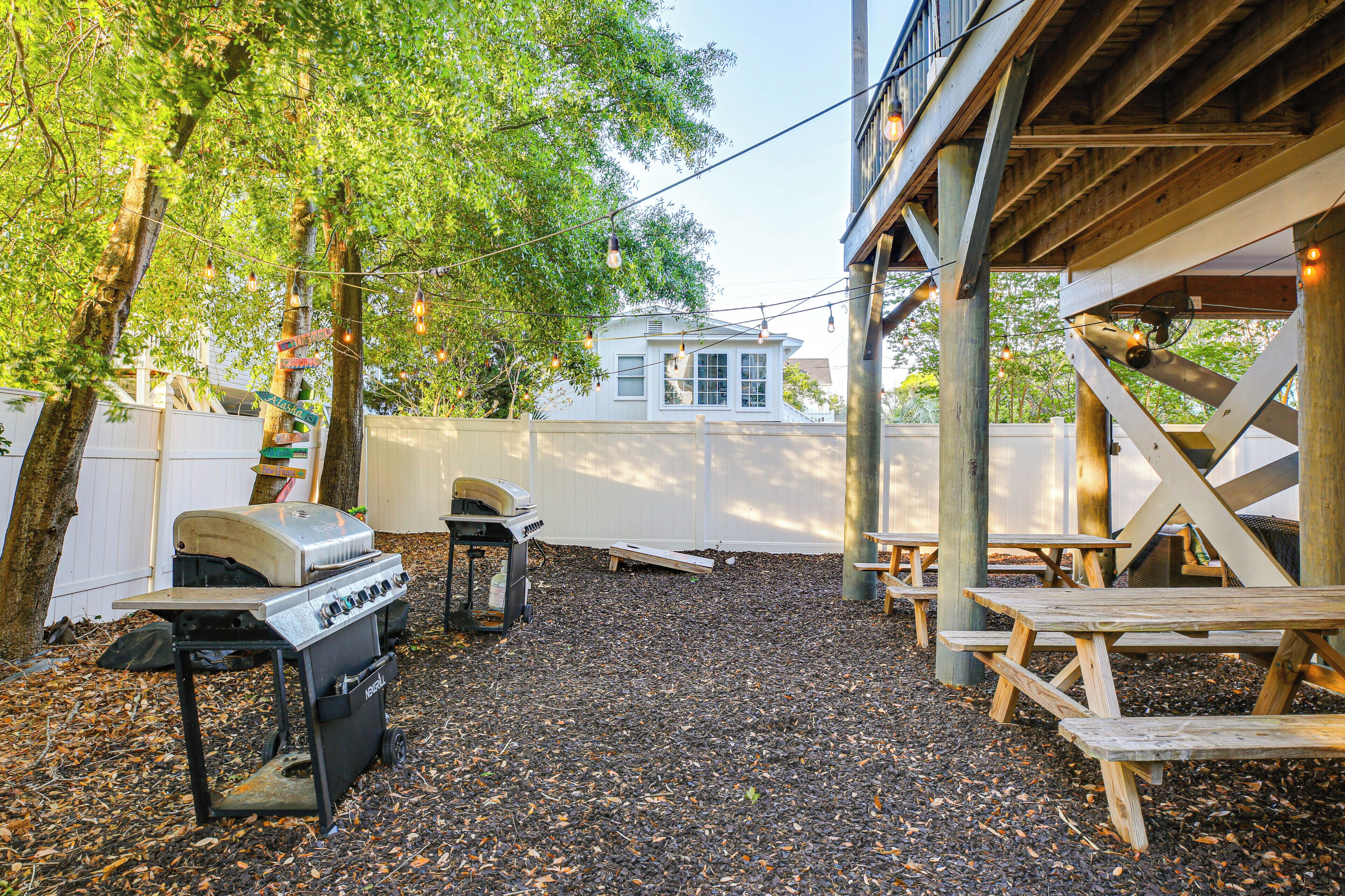 A backyard with a barbecue grill, picnic tables, and a covered area.