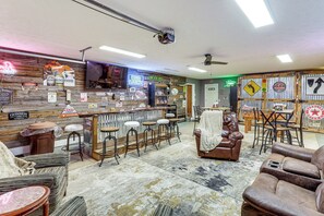A bar area with stools, a bar counter, and a variety of beer signs.