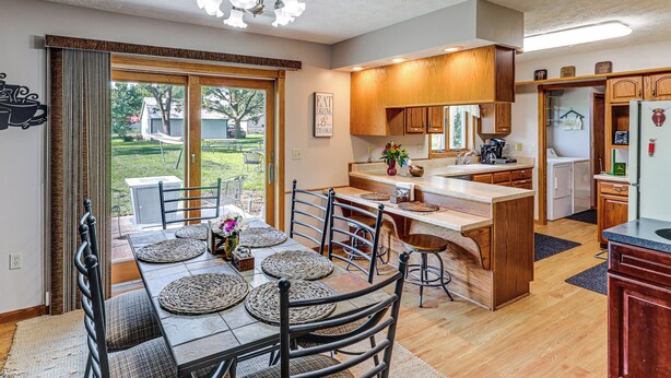 A kitchen with a dining area, wooden cabinets, a refrigerator, and a view of the outdoors.