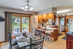 A kitchen with a dining area, wooden cabinets, a refrigerator, and a view of the outdoors.