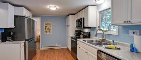A kitchen with white cabinets, stainless steel appliances, a window, and a sink.