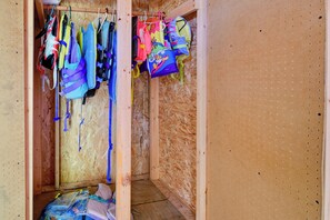A room with wooden walls, a bed with a blue and white cover, and a closet with hanging bags. - Waterfront Days, Fireside Nights! Lake Helen Haven (Rosholt)
