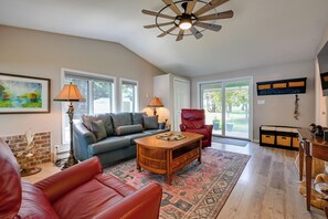A living room with a sofa, armchair, coffee table, and a ceiling fan.