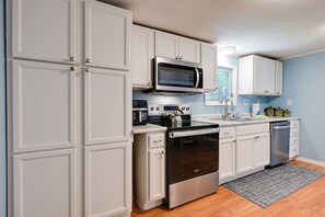 A modern kitchen with white cabinetry, stainless steel appliances, and a wooden floor. - Waterfront Days, Fireside Nights! Lake Helen Haven (Rosholt)