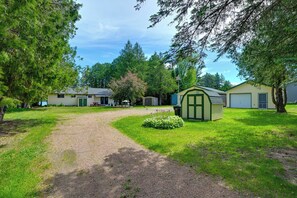 A residential area with a gravel driveway, a small garden, and a green shed. - Waterfront Days, Fireside Nights! Lake Helen Haven (Rosholt)