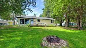 Een huis met een vuurkorf in de tuin, omringd door bomen en een verzorgd gazon.
