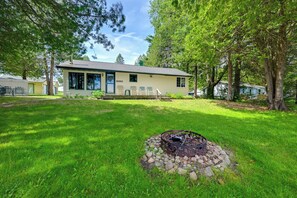 A house with a fire pit in the yard, surrounded by trees and a well-maintained lawn.
