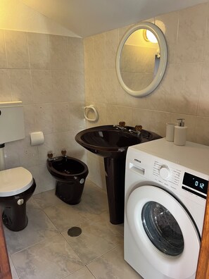 A bathroom with a toilet, bidet, sink, and washing machine.